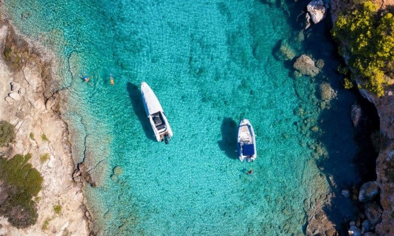 Aerial view of moored rib boats with snorkelers and swimmers at